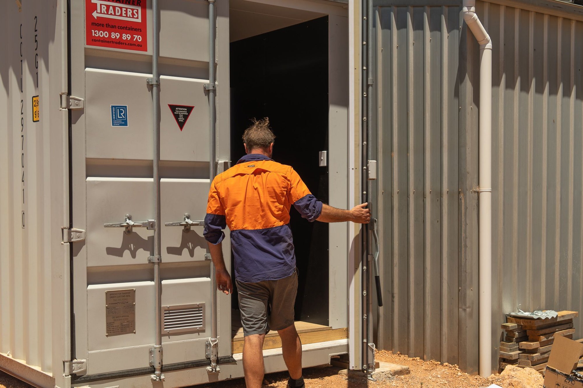 Greg, lead electrician, opening the doors of a containerised off grid power system at quondong station south australia.