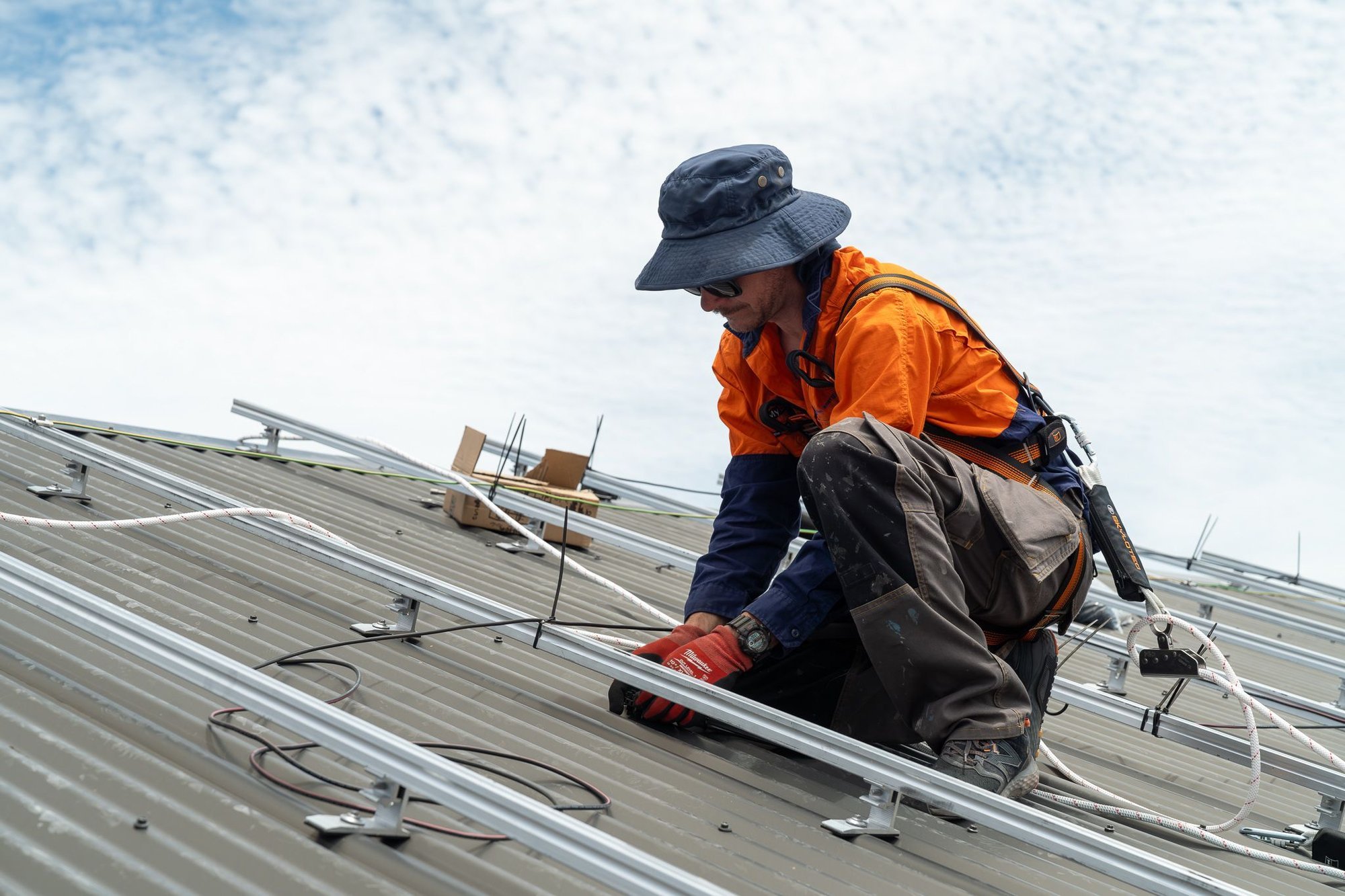 a myenergy engineering electrician on a roof installing a roof mounted solar panel array